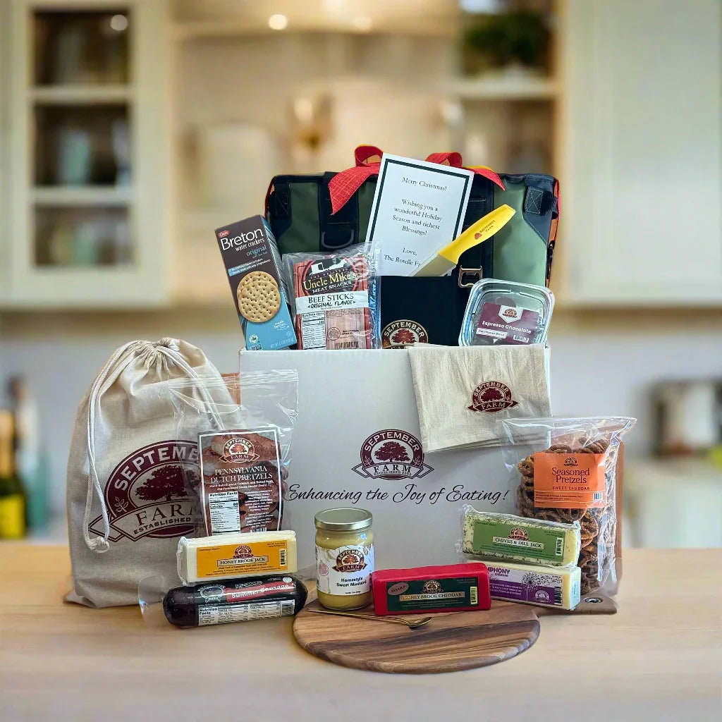 Gift basket with various items including a white box, a bag, and a cutting board on a wooden surface.